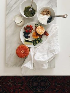 a white plate topped with food next to bowls filled with fruit and veggies