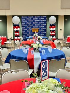 a room filled with tables covered in red, white and blue table cloths next to balloons