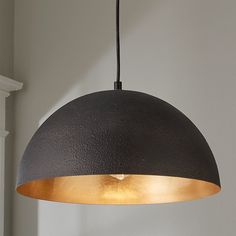 a black and gold colored light hanging from a ceiling fixture in a room with white walls