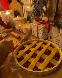 a pie sitting on top of a wooden table next to candles and other items in the background