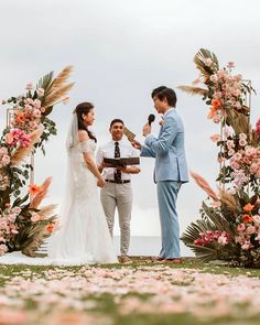 a bride and groom are getting married under an arch with flowers on the grass outside