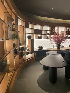 a man sitting at a round table in a room with shelves and potted plants