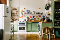 a kitchen with green cabinets and wooden floors, white appliances and an open shelving unit