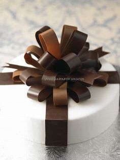 a white cake with brown ribbon on top