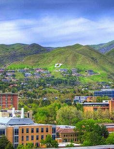 a city with mountains in the background and trees on the other side that are green