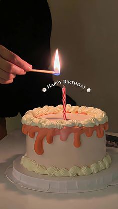 a person lighting a candle on a birthday cake