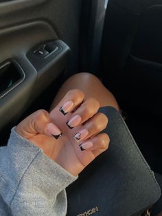 a woman's hand with black nail polish on her nails in the back seat of a car