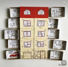 several boxes with drawings on them are arranged in the shape of small houses and a red car