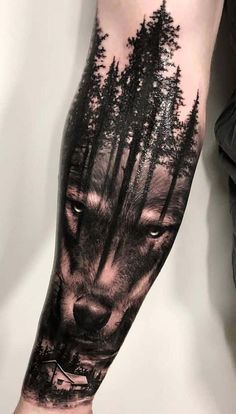 a man's arm with a wolf and trees on it