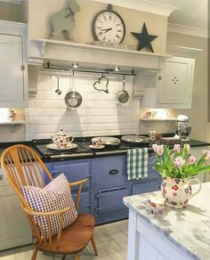 a kitchen with blue cabinets and white countertops has a large clock above the stove