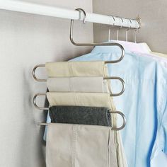 clothes hanging on a rail in front of a wall mounted coat rack with five pants