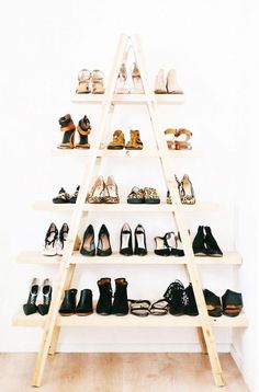 there is a ladder that has many pairs of shoes on it in front of a white wall