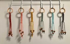 there are many different colored ropes hanging from the hooks on the wall with wooden beads