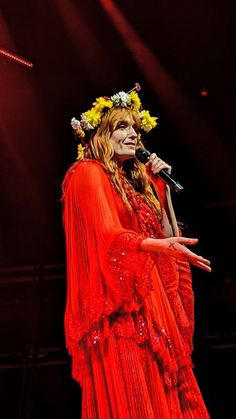 a woman wearing a red dress and holding a microphone in front of her face on stage