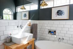 a bathroom with two sinks and a bathtub next to each other in front of three framed pictures