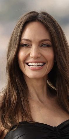 a woman with long brown hair smiling at the camera