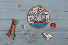 a cross - stitch pattern with a sailboat on it next to some scissors and flowers