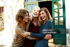 three women hugging each other in front of a house