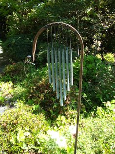 a metal wind chime in the middle of some bushes