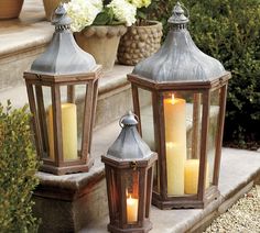 two metal lanterns with lit candles on the steps