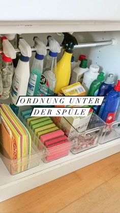 an organized under the sink drawer with cleaning products and other items in it on top