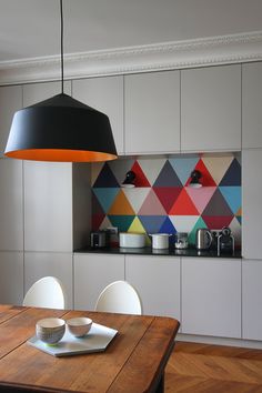 an instagramted photo of a kitchen with colorful tiles on the wall