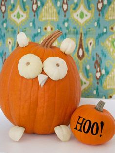 two pumpkins with faces painted on them sitting next to each other in front of a wall