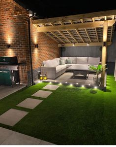 an outdoor living area is lit up with lights and green grass on the ground,