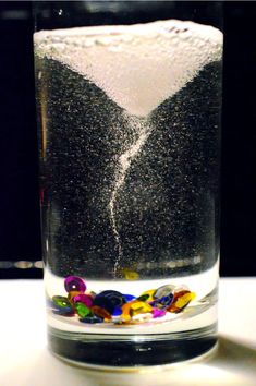 a glass filled with liquid and beads on top of a table