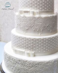 a three tiered white wedding cake with intricate designs on the top and bottom layer