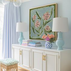 a blue and white vase sitting on top of a dresser next to a painting with pink flowers