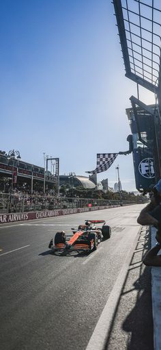 a man driving a race car on a track with people watching from the sidelines