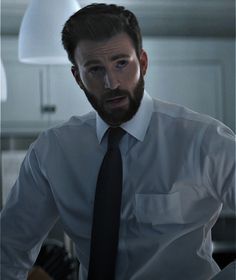 a man with a beard wearing a white shirt and black tie standing in a kitchen