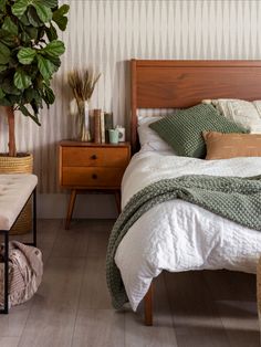 a bedroom with a bed, nightstands and a potted plant