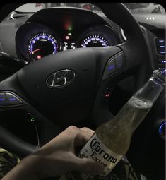 a person is holding a bottle in their hand while sitting in the driver's seat of a car