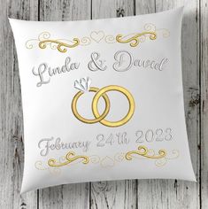 two gold wedding rings on a white pillow with the words carol and james written on it