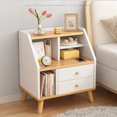 a white and wooden shelf with some books on top of it next to a bed