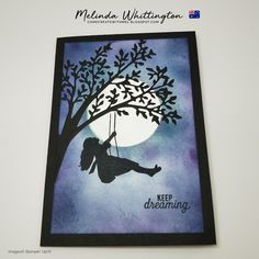 a card with a silhouette of a girl swinging on a tree and the moon in the background