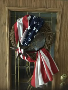 an american flag wreath on a door with two ribbons hanging from it's side