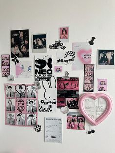 a white wall covered in pictures and magnets next to a pink heart shaped object