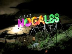 a neon sign that reads, visit noogales at night with the moon in the background