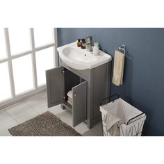 a white sink sitting under a bathroom mirror next to a trash can and towel dispenser