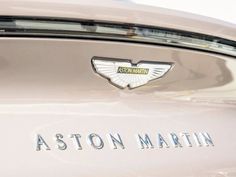 the back end of a pink car with a badge that reads aston martin on it