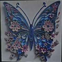 a blue butterfly with pink and purple flowers on it's wings, made out of beads