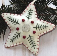 an ornament shaped like a star hanging from a christmas tree on a white wooden background