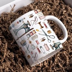 a coffee mug with sewing related items on it in a pile of wood shavings