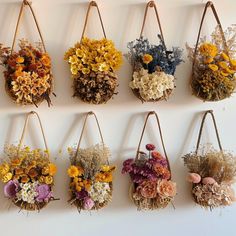 a bunch of flowers are hanging on the wall in different shapes and sizes, along with straw bags