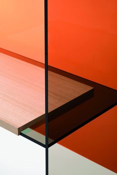 a wooden table with glass shelves in front of an orange wall