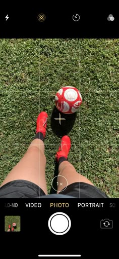 a person wearing red shoes standing in the grass with a soccer ball on their feet