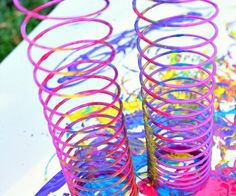 three colorful spirals sitting on top of a table covered in paint